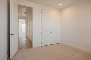 Unfurnished bedroom with light colored carpet, a closet, and recessed lighting