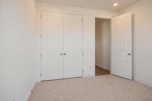 Unfurnished bedroom featuring light colored carpet, a closet, and recessed lighting