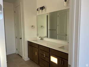 Full bathroom with dark tile patterned flooring and double vanity