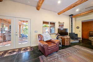 Living room with finished concrete flooring, a wood stove, beamed ceiling, french doors, and recessed lighting