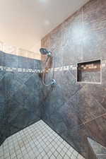 Full bath featuring tiled shower and a textured ceiling