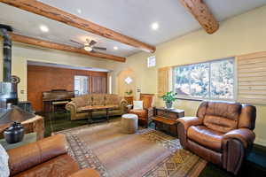 Living area featuring a wood stove, plenty of natural light, beam ceiling, recessed lighting, and arched walkways