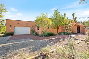 Pueblo revival-style home featuring stucco siding, driveway, and a garage