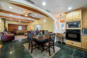 Dining space with recessed lighting, arched walkways, beamed ceiling, healthy amount of natural light, and concrete flooring
