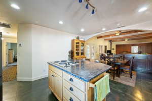 Kitchen featuring light brown cabinetry, recessed lighting, a kitchen island, arched walkways, and a textured ceiling