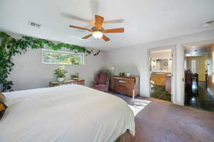 Carpeted bedroom with ceiling fan and connected bathroom