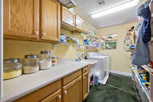Washroom with a textured ceiling, washing machine and clothes dryer, cabinet space, and concrete floors