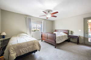 Bedroom with carpet flooring, ceiling fan, and a textured ceiling