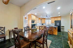 Dining area featuring recessed lighting, a textured ceiling, arched walkways, and concrete flooring