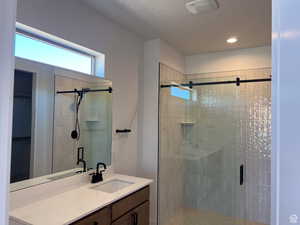 Full bath featuring vanity, a shower stall, recessed lighting, and a spacious closet