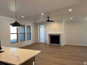 Unfurnished living room featuring light wood-type flooring, recessed lighting, a fireplace, a ceiling fan, and a textured ceiling