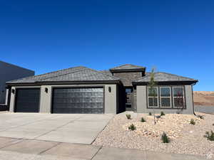 Prairie-style home featuring stucco siding, a garage, and driveway