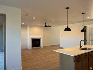 Kitchen featuring open floor plan, recessed lighting, light wood-style flooring, pendant lighting, and light stone counters