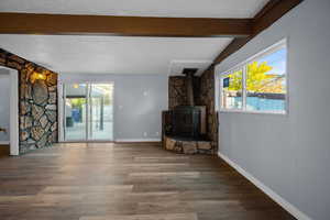 Unfurnished living room with a wood stove, wood finished floors, and a textured ceiling