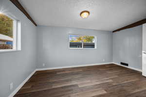 Unfurnished room featuring dark wood finished floors and a textured ceiling