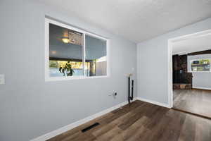 Spare room with dark wood-style flooring, a textured ceiling, and a stone fireplace