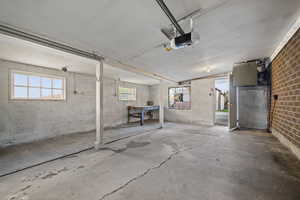 Garage featuring concrete block wall, a garage door opener, and a heating unit
