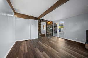 Unfurnished living room featuring a textured ceiling, beam ceiling, and dark wood-style flooring