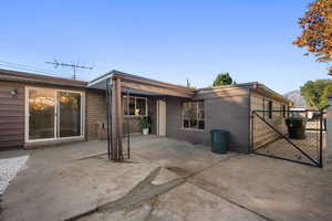 Rear view of property featuring a patio area, a gate, and stucco siding