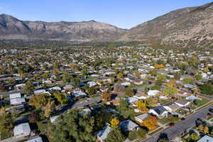 Aerial view of property and surrounding area featuring a mountainous background and nearby suburban area