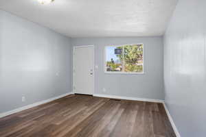 Unfurnished room with a textured ceiling and dark wood finished floors
