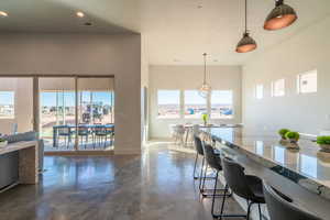 Kitchen featuring hanging light fixtures, finished concrete floors, light stone counters, a breakfast bar area, and recessed lighting