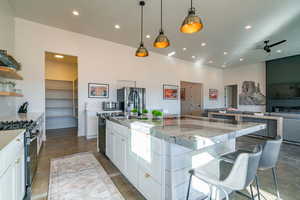 Kitchen featuring white cabinetry, finished concrete flooring, pendant lighting, stainless steel appliances, and open floor plan