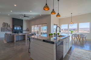Kitchen featuring finished concrete flooring, decorative light fixtures, open floor plan, black dishwasher, and a kitchen breakfast bar
