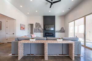 Living room featuring finished concrete flooring, recessed lighting, a glass covered fireplace, and ceiling fan