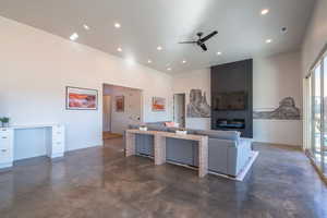 Living room featuring finished concrete floors, a ceiling fan, a glass covered fireplace, recessed lighting, and built in study area