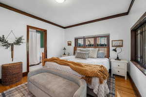 Bedroom with ornamental molding and wood finished floors