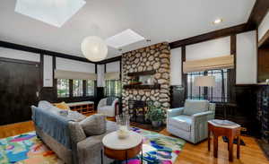 Living room featuring a fireplace, a skylight, wood finished floors, and healthy amount of natural light