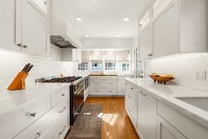 Kitchen featuring range with gas stovetop, tasteful backsplash, white cabinetry, and recessed lighting