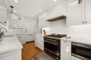 Kitchen with range with gas cooktop, hanging light fixtures, glass insert cabinets, white cabinets, and recessed lighting