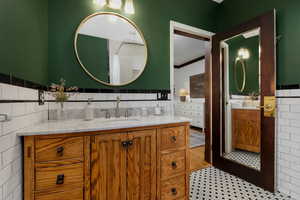 Bathroom featuring tile walls, vanity, light tile patterned floors, a tile shower, and crown molding