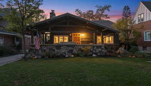 View of front facade featuring a chimney, a yard, and a porch