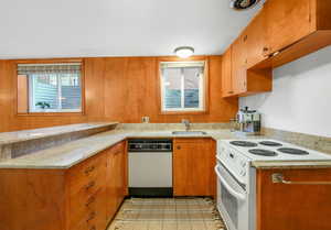 Kitchen featuring white appliances, a peninsula, brown cabinets, and light stone countertops
