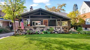 View of front of property with a front yard, a chimney, and a porch