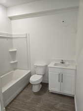 Bathroom with vanity, dark wood-style floors, and tub / shower combination