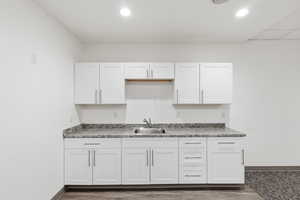 Club room with kitchen with white cabinets and dark wood finished floors