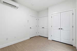 Bedroom featuring a wall mounted mini split, light wood-style flooring, and multiple closets