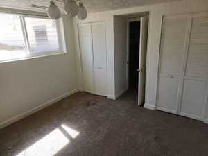 Unfurnished bedroom featuring two closets and dark colored carpet