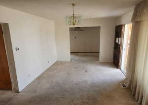 Unfurnished dining area featuring carpet, a chandelier, and a ceiling fan