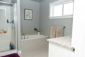 Bathroom featuring vanity, a shower stall, and a garden tub