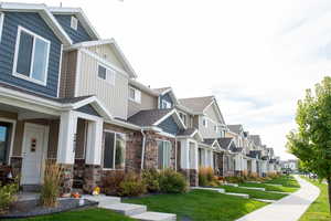 View of property exterior with a residential view, stone siding, a lawn, board and batten siding, and covered porch