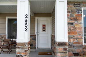 Property entrance featuring stone siding and covered porch