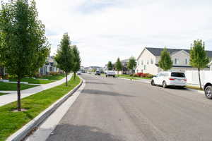 View of asphalt street with curbs, a residential view, and sidewalks