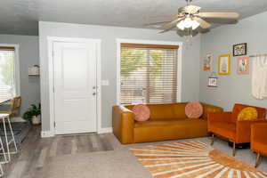 Living area with wood finished floors, a ceiling fan, and a textured ceiling