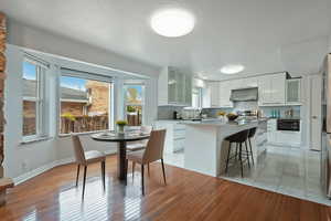 Kitchen featuring glass insert cabinets, a breakfast bar, white cabinetry, a center island, and a textured ceiling