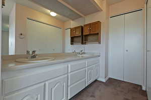 Full bath with double vanity and dark colored carpet